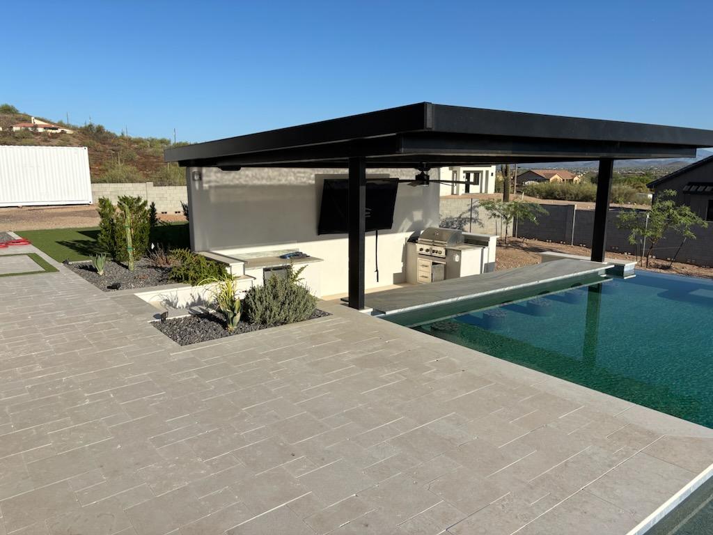 Pool with covered pergola, outdoor kitchen and paver deck by DCM Pools — Arizona