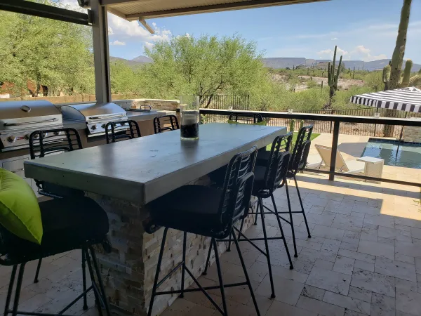 Outdoor kitchen and bar seating with pool view by DCM Pools — Arizona