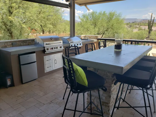 Custom outdoor kitchen with grills and stone island by DCM Pools — Arizona
